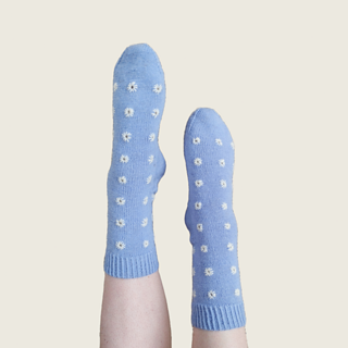 The same blue socks with white embroidery on feet in air.