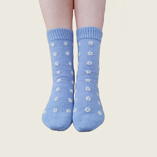 The same blue socks with white eyelet embroidery on standing feet.