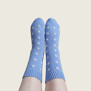 Blue socks with white eyelet emrboidery on feet stretched out in front of the camera.