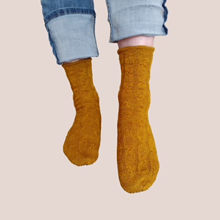 The same mustard-gold socks on standing feet, one foot extended.
