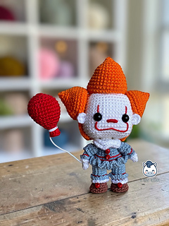 Handmade Pennywise amigurumi inspired by IT featuring a red balloon, a geek crochet pattern PDF perfect for Halloween and horror fans.
