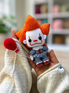 Handmade Pennywise amigurumi inspired by IT featuring a red balloon, a geek crochet pattern PDF perfect for Halloween and horror fans.