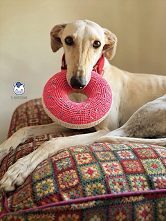 Crochet donut dog toy handmade with pink and beige yarn, a colorful DIY pet-friendly toy ideal for greyhounds and large dogs.
