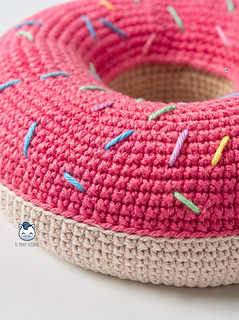 Crochet donut dog toy handmade with pink and beige yarn, a colorful DIY pet-friendly toy ideal for greyhounds and large dogs.