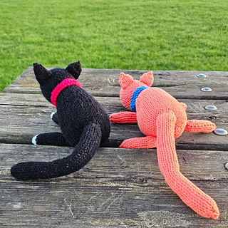 Two cute knitted cats on a park bench