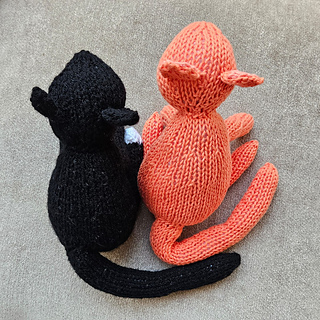 Two cute knitted cats on a cushion