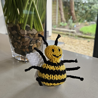 Knitted bee display next to vase
