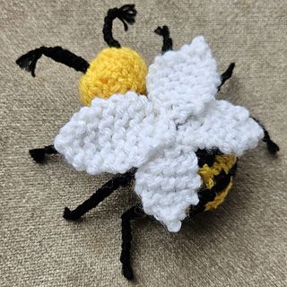 Knitted bee toy sitting on cushion