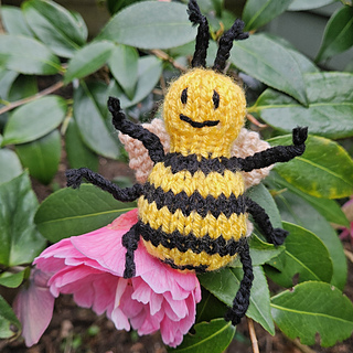 Knitted bee toy sitting on flower