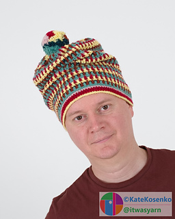 A man in a playful striped crochet beanie with a pompom.
