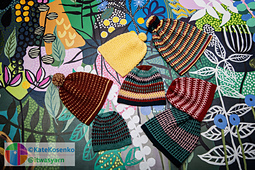 Seven colorful crochet hats in mosaic and striped patterns, featuring fitted and slouchy shapes with some topped by pom-poms.