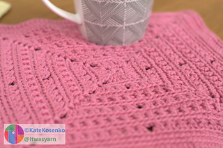 A close-up of a textured square crocheted with light worsted yarn.