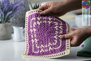 A textured crochet square with V-stitches, made from light worsted yarn, perfect for dishcloths or washcloths.