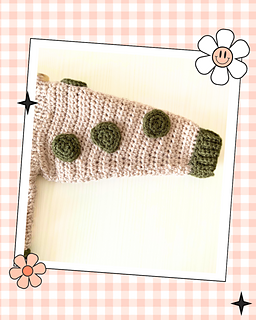 beige crochet sweater with moss green cuff, featuring a moss green dinosaur applique, mustard and moss green spikes run down the spine of the dinosaur. the dinosaur has white teeth and googly eye. the sleeves of the jumper has crochet spots sewn to them. dinotastic crochet sweater pattern for babies and toddlers by jane burns