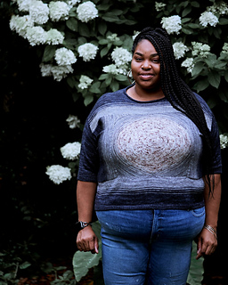 Raqiya has a 60"/150 cm bust and is wearing a size P, which has a finished bust of 62"/155 cm. Sizing down for less ease results in a slightly cropped top, as shown. Uses Less Traveled Yarn Paloma.