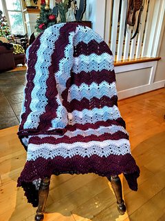 Photo contributed by Amber Fernandez.  Close-up view of the California Dreamin’ Lapghan, highlighting rhythmic ripple stitches and a softly draping fabric.
California Dreamin’ Lapghan shown in soft blue and deep plum, featuring flowing ripple stitches and elegant texture.