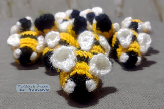 A collection of small crochet bees with black and yellow stripes. They are facing the camera and arranged in a bee formation.