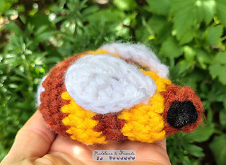 A palm sized crochet bee in brown and yellow.