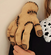 The life-sized Thing hand, with fingers curled into a "walking" pose on a wooden table, as a unique horror-themed prop.