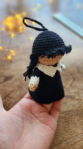 Close-up of the tiny Amigurumi doll's face, highlighting the signature braids and white crochet collar detail