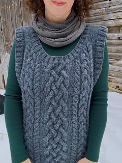 A close-up detail of the front chest of a blue cabled vest.