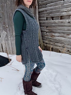 A female is standing side view in front of a barn wall. Showing detail of side buttons on vest.