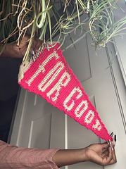 Person holds pink and white Wicked For Good pennant flag