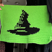 Green and black tapestry features the image of a witch hat