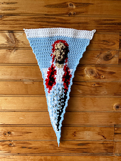White and blue crochet pennant features image of Dorothy Gale