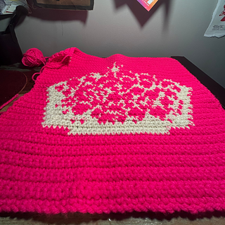 Pink and white crown tapestry lies flat on a desk