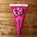 Pink and white crochet pennant hangs on a wooden wall