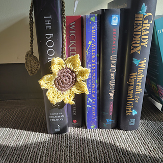 Sunflower bookmark with leaf stem draped over the spines of books