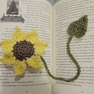 Sunflower bookmark on top of an open book. Green stem with leaf variation.