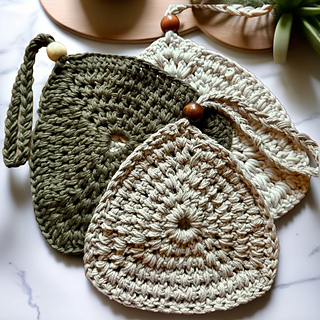Neutral farmhouse-style crochet trivet in cotton yarn, styled on a wood cutting board beside a mug and utensils.