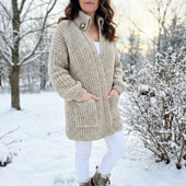 Chunky crochet cardigan made with oatmeal yarn featuring a rolled collar and pockets on a model in the snow, showing the warmth
