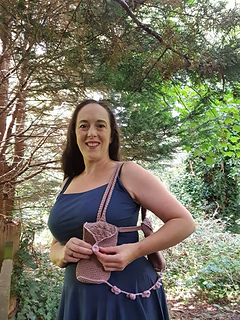Woman in forest holding brown and pink crocheted bag with flowers