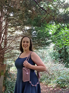 Woman in forest holding brown and pink crocheted bag with flowers