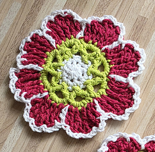 crocheted red and white flower coasters with green detail