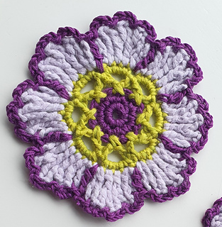 crocheted dark and light purple flower coaster with green detail