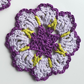 crocheted dark and light purple flower coaster with green detail