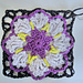crocheted lilac and violet flower coaster with green detail and black edging 