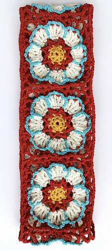crocheted yellow, red white and turquoise flower squares sewn into a strip