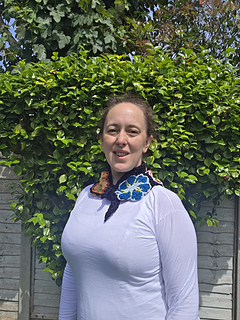 Black lace neckerchief with bright floral granny squares worn with point at back, tied at front (from front)