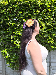 Black lace headscarf with bright floral granny squares worn, seen from side