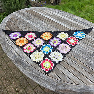 Black lace triangular shawl with bright floral granny squares laid flat