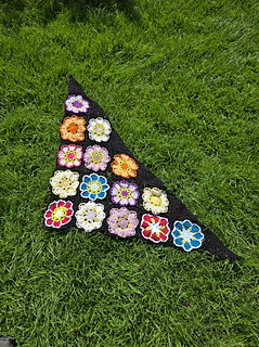 Black lace triangular shawl with bright floral granny squares laid flat