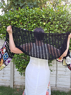 Black lace rectangular shawl with bright floral granny square border at short ends held up behind wearer