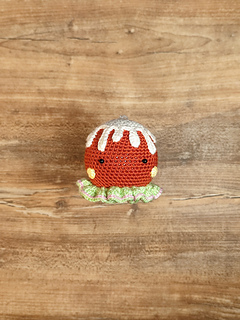 Crocheted gingerbread brown head, white icing details, and colorful decorative buttons. Put on the table.