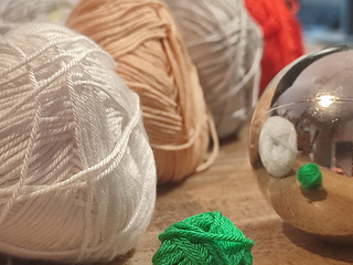 White, beige, gray, red, green yarn skeins, plain Christmas bauble.