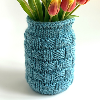 Blue knitted jar cozy with tulips on a white background.